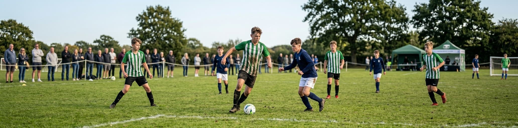 Young players at a grassroots football tournament, parents watching on the sidelines
